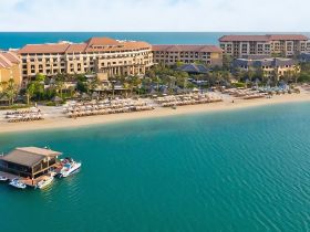 Aerial view of a beachfront resort with a dock featuring jet skis, showcasing a perfect destination for water sports and relaxation.