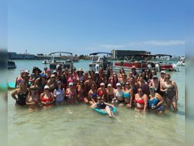 A vibrant group of women enjoys a fun day in the water, celebrating together with drinks and laughter, surrounded by boats — perfect for a bachelorette party or girls' trip.