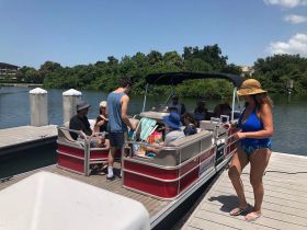 A lively group gathers on a pontoon boat at the dock, ready for a fun day on the water — perfect for family outings or group celebrations.
