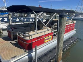 A vibrant red pontoon boat docked at the marina, showcasing its spacious seating and perfect for leisurely outings on the water.