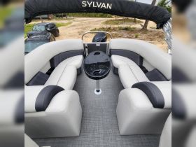 Interior view of a Sylvan pontoon boat showcasing spacious seating and a central table, perfect for relaxing and socializing on the water.