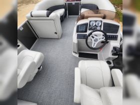 Interior view of a modern pontoon boat showcasing spacious seating and a well-equipped helm, perfect for comfortable cruising on the water.