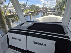 A view of the helm area inside a boat, featuring a SIMRAD console and a sleek design, perfect for navigation and control.