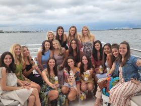 A lively group of friends enjoys a fun celebration aboard a boat, capturing the joy of their outing with drinks and smiles against a scenic backdrop.