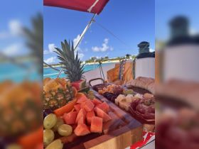 A beautifully arranged charcuterie board featuring fresh fruits and meats, perfect for enjoying on a boat trip under the sun.