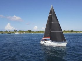 A stunning aerial view of a sailboat gracefully navigating through clear waters, surrounded by a picturesque coastline — perfect for sailing enthusiasts and adventure seekers.