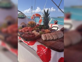 A beautifully arranged charcuterie board featuring a variety of fruits, cheeses, and meats, perfect for enjoying on a boat trip in the sun.