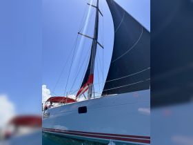 A striking view of a sailboat with its sails raised, showcasing the vessel's sleek design against a clear blue sky — perfect for sailing enthusiasts and adventure seekers.