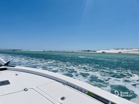 A scenic view from the bow of a boat cruising through clear waters, showcasing the beautiful coastline and sandy shores in the distance.