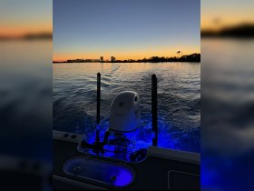 A serene sunset view from the back of a boat, showcasing the engine and tranquil waters — perfect for evening cruises.