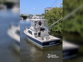 A fishing boat named 'TANGIER II' is docked in a serene marina, showcasing its sleek design and readiness for adventure on the water.