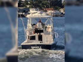 The 'TANGIER II' boat is seen underway, showcasing its sleek design as it navigates through the water, perfect for fishing or leisure trips.