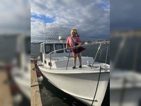 A cheerful child stands on the bow of a fishing boat, enjoying a day on the water — a perfect moment for family adventures and fishing trips.