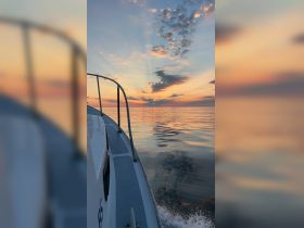 A serene view of a boat cutting through calm waters at sunset, showcasing the tranquil beauty of evening cruises.