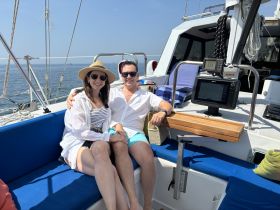 A couple enjoys a sunny day on a sailboat, relaxing together on the deck — perfect for romantic getaways or sailing adventures.