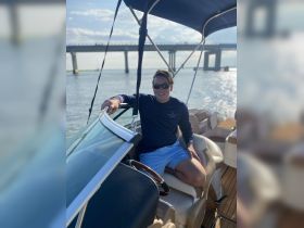 A man relaxes on the deck of a boat, enjoying a sunny day on the water — perfect for leisure and adventure outings.