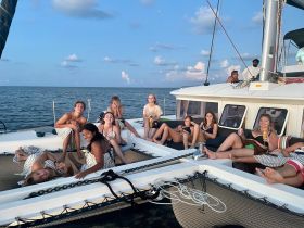 A lively group enjoys a fun day aboard a catamaran, relaxing and celebrating on the water — perfect for summer gatherings and memorable outings.