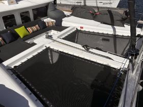A cozy lounge area on a catamaran featuring colorful cushions and a spacious layout, perfect for relaxing while enjoying the sea breeze.