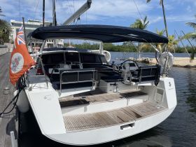 A sleek catamaran docked with a beautiful backdrop of palm trees and clear skies, showcasing its elegant design and spacious deck.