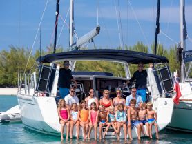 A joyful group of adults and children pose together on the steps of a yacht, capturing a memorable family outing on the water.