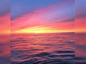 A stunning sunset paints the sky in vibrant hues over the tranquil ocean, creating a picturesque scene perfect for romantic evenings or peaceful reflections on the water.