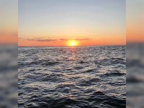 A breathtaking sunset over the ocean, casting vibrant colors across the water — a perfect moment for relaxation and reflection on a boating adventure.