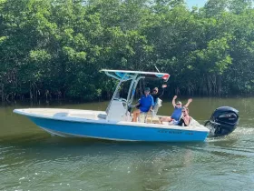 A cheerful group waves from their boat while cruising through mangrove waters, capturing the essence of fun and adventure on the water.