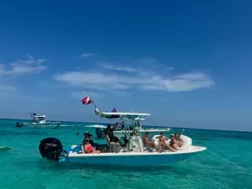 A lively group enjoys a day on the water, relaxing on a boat in crystal-clear waters, perfect for snorkeling and fun in the sun.