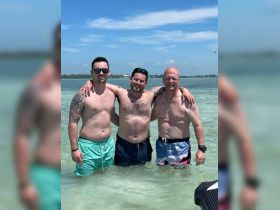 Three friends enjoy a sunny day in the shallow waters, celebrating friendship and fun at the beach.