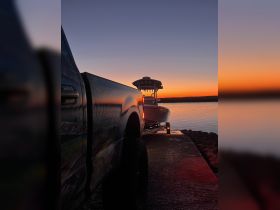 A serene sunset view featuring a boat on a trailer at the dock, highlighting the tranquil atmosphere of an evening on the water.