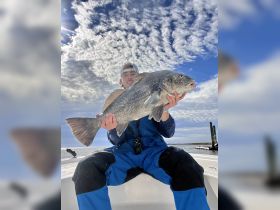 An enthusiastic angler proudly displays a large catch while fishing on a boat, showcasing the thrill of outdoor adventures.