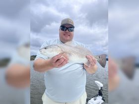 A proud angler displays his impressive catch while fishing on the water, showcasing the thrill of outdoor adventures.
