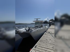 A sleek center console boat docked at a serene waterfront, showcasing its modern design against a clear blue sky.