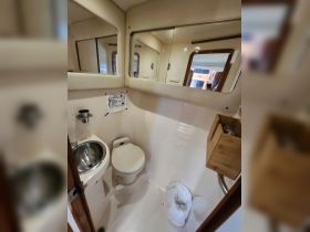 A clean and functional bathroom inside a boat, featuring a sink and toilet, ideal for comfortable cruising.