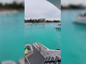 A scenic view from a boat showcasing the stunning turquoise waters and beachgoers enjoying the shoreline, perfect for a relaxing day on the water.
