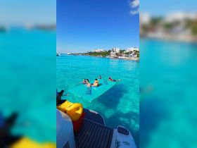 A lively group enjoys a fun day on a floating mat in the stunning turquoise waters, perfect for family adventures and summer outings.