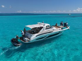 A lively group enjoys a day on a luxurious yacht in stunning turquoise waters, with a jet ski ready for adventure. Perfect for unforgettable boating experiences.