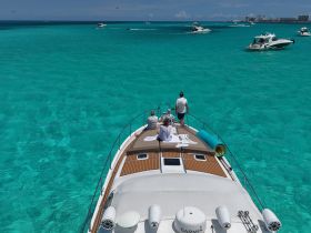 A couple enjoys a relaxing moment on the deck of a yacht, surrounded by stunning turquoise waters — an ideal setting for a luxurious day on the water.