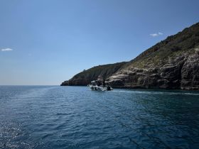 A scenic view of a boat navigating through calm waters near a rocky coastline, showcasing the beauty of maritime adventures.