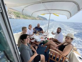 A cheerful group enjoys a meal aboard a boat, surrounded by stunning ocean views — perfect for family outings and memorable boating experiences.