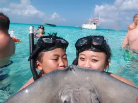 Two children interact closely with a stingray while snorkeling in clear turquoise waters, creating a memorable wildlife experience in the ocean.