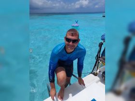 A man climbs aboard a boat after enjoying a swim in the crystal-clear waters, showcasing the fun and excitement of water activities.