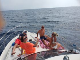 A lively group enjoys drinks and relaxation on the deck of a yacht, perfect for sunbathing and celebrating special moments on the water.