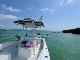 A scenic view of a charter boat with guests enjoying a floating mat in the turquoise waters, perfect for a relaxing day on the water.