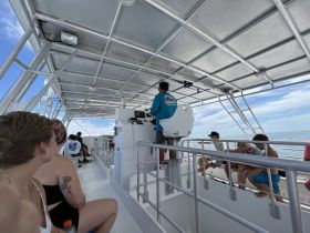 Inside view of a boat's helm area, showcasing guests seated and enjoying the ride. The spacious cabin design offers a comfortable experience for all aboard.