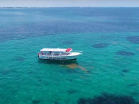 A stunning aerial view of a glass bottom boat cruising through crystal-clear turquoise waters, perfect for exploring marine life and enjoying scenic tours.
