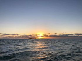 A stunning sunset over the ocean, capturing the serene beauty of the horizon — perfect for tranquil evening boat rides.