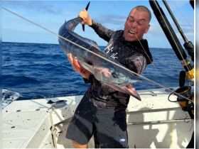 An angler celebrates a successful catch while fishing in the open ocean, showcasing the thrill of deep-sea fishing adventures.