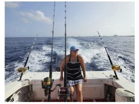 A woman enjoys a fishing trip on a boat, surrounded by the vast ocean — a perfect day for fishing enthusiasts.