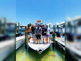 A group of friends poses on the bow of a fishing boat, celebrating their day on the water — perfect for fishing trips and memorable outings.